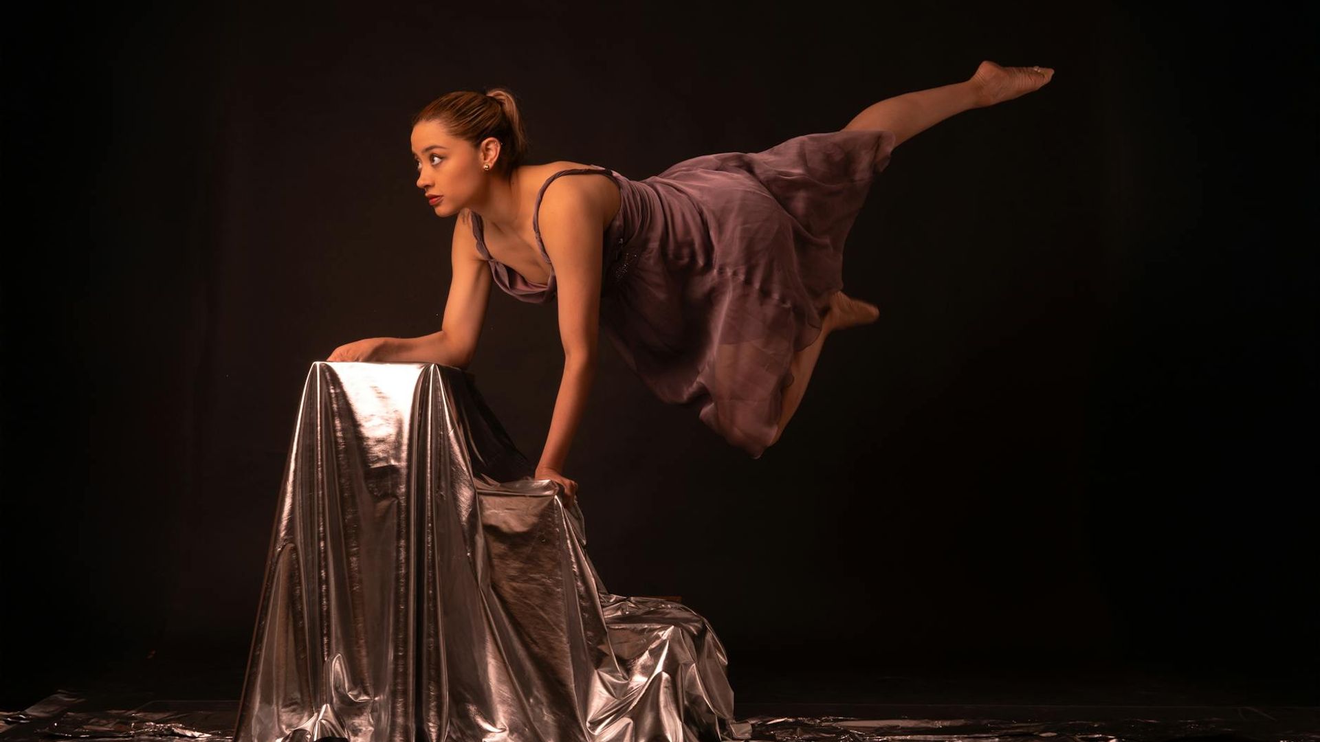 Athletic person doing rhythmic movements in a dark modern studio.