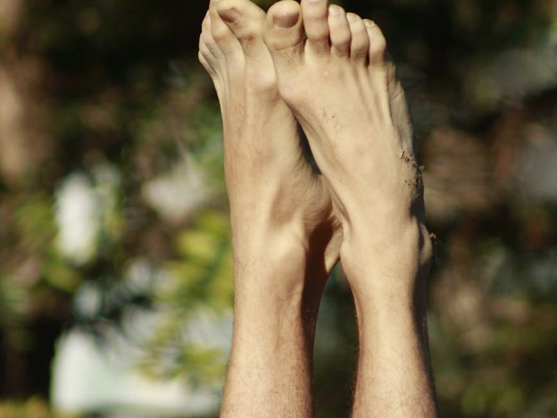 Person hands reaching for feet in a stretching pose.